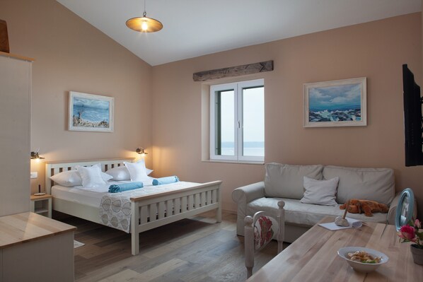 A bedroom with a bed, bedside table, nightstand, and a window with a view.