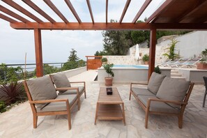 An outdoor patio with wooden furniture, a pool, and a stone wall. - Kate in Podgora With 2 Bedrooms and 2 Bathrooms (Podgora)