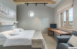 Ein Schlafzimmer mit Bett, Schreibtisch, Stuhl und Fenster.