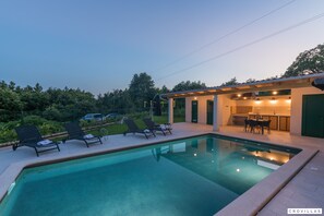 Ein Pool mit Liegestühlen und einer kleinen Außenküche.