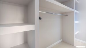 Un armario blanco con varios estantes y espacio para colgar.