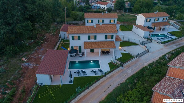 Eine großzügige Villa mit Swimmingpool, mehreren Sitzbereichen im Freien und einem gepflegten Garten.
