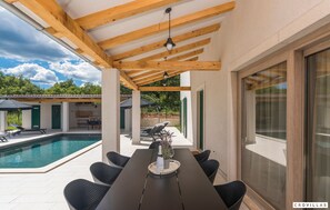 Un espace extérieur abrité comprenant une piscine, une table à manger et des chaises.