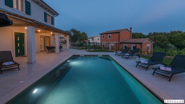 Una piscina con sillas de descanso y un área de patio techada.