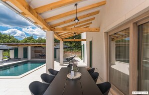 Zona exterior coberta amb piscina, taula de dinar i cadires.