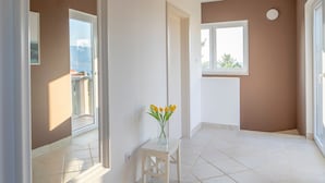 A spacious room with a large window, a small table with a vase of flowers, and a tiled floor. - Stella Hvar in Rudina Hvar (Stari Grad)