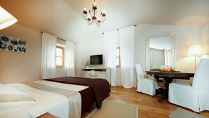 A hotel room with a bed, a desk with a chair, a television, and a dining table with chairs. - Benvenuti in Motovun (Motovun)