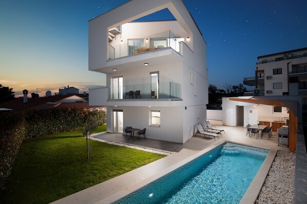 A modern multi-story house with a swimming pool, outdoor seating, and a clear night sky. - Tina Ocean View in Medulin (Medulin)