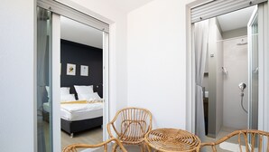 Une chambre d’hôtel avec un lit, une salle de bain avec douche et des meubles en osier.