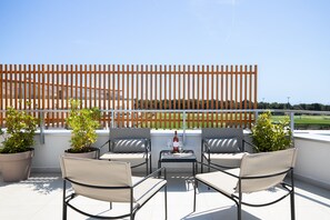 A terrace with outdoor seating, potted plants, and a table with a bottle and glass. - Tina Ocean View in Medulin (Medulin)
