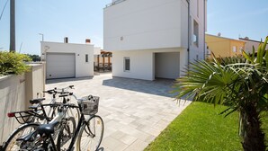 Un bâtiment moderne doté d’un garage, d’une allée pavée et d’un petit jardin agrémenté d’un palmier.
