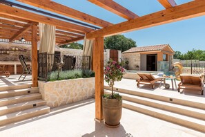 A covered outdoor area with wooden beams, stone steps, and a potted plant.