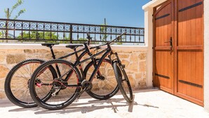 A bicycle parked next to a wooden gate, with a stone wall and a metal fence in the background. - Josipovi Dvori in Skradin (Skradin)