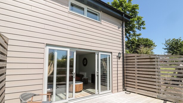 A modern house with a deck, sliding glass doors, and a wooden fence.