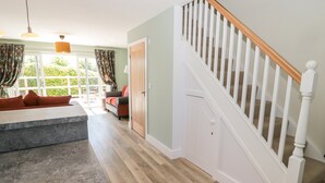 A modern kitchen with a granite countertop, a dining area with a red sofa, and a staircase with white railings.