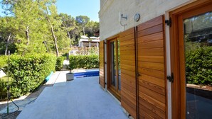 A modern building with a wooden door and a glass door, surrounded by greenery and a clear sky. - Bianco in Grohote Rogac Olta (Solta)