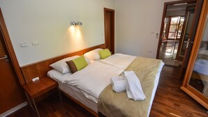 A hotel room with a wooden bed, a nightstand, a mirror, and a door leading to a balcony. - Bianco in Grohote Rogac Olta (Solta)