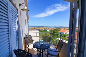 A balcony with a table and chairs, a hanging light fixture, and a view of a town with red-roofed buildings. - Kos in Murter With 11 Bedrooms and 6 Bathrooms (Murter-Kornati)