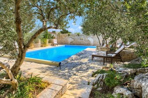 A swimming pool with stone walls and a patio area with lounge chairs. - Kos in Murter With 11 Bedrooms and 6 Bathrooms (Murter-Kornati)
