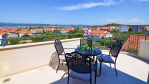 Ein Balkon mit Tisch und Stühlen mit Blick auf ein Wohngebiet mit roten Dächern.