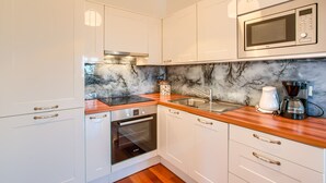 Eine moderne Küche mit weißen Schränken, einem Backofen, einer Mikrowelle und einer Kaffeemaschine.