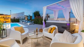 A poolside area with white lounge chairs, a hot tub, and a table with a bottle of champagne. - Amia in Pula With 3 Bedrooms and 2 Bathrooms (Pula)