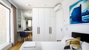 Moderni hotellihuone, jossa on suuri sänky, työpöytä ja vaatekaappi.