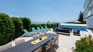 Un área de estar al aire libre con piscina, sillas de descanso y una mesa.