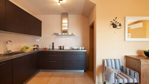 Una cucina moderna con mobili scuri, una cappa in acciaio inossidabile e un pavimento piastrellato.