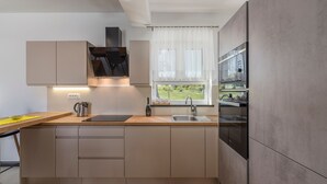 Una cocina moderna con encimera de madera, electrodomésticos integrados y ventana con vistas al verdor.