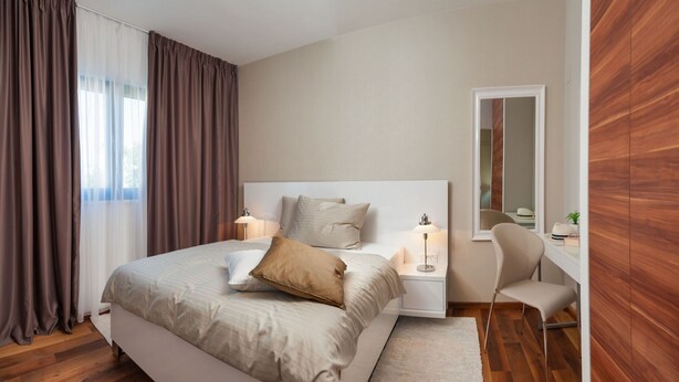 A modern bedroom with a large bed, bedside lamps, a chair, and a mirror. - Sunce in Okrug Gornji (Okrug)