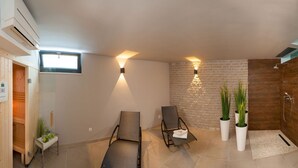 A modern bathroom with a freestanding bathtub, a wooden sauna, and a seating area with chairs and plants. - Sunce in Okrug Gornji (Okrug)
