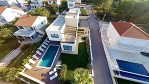 An aerial view of a residential area with modern houses, a swimming pool, and a well-maintained lawn. - Sunce in Okrug Gornji (Okrug)