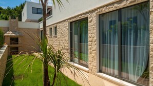 A modern house with stone facade, large sliding glass doors, and a well-maintained lawn. - Sunce in Okrug Gornji (Okrug)
