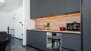 A modern kitchen with dark cabinetry, a wooden countertop, and a built-in oven. - Alison Labin in Zupanici (Sveta Nedelja)