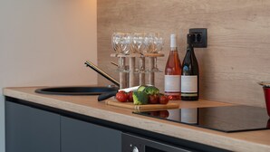 A kitchen counter with a wine bottle, glasses, and vegetables. - Alison Labin in Zupanici (Sveta Nedelja)