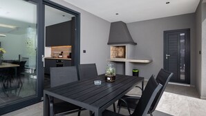 A modern kitchen with a built-in stove, a dining area with a table and chairs, and a glass door leading to an outdoor space. - Alison Labin in Zupanici (Sveta Nedelja)