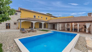 A swimming pool with a stone deck, a yellow building with arches, and a stone wall. - Lanca in Sveti Lovre (Sveti Lovrec)
