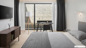 A modern hotel room with a large bed, a desk, and a TV. - Eden in Li Njan With 4 Bedrooms and 4 Bathrooms (Liznjan)