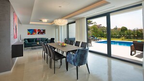A modern dining area with a large table, chairs, and a view of a swimming pool. - Spuga in Brodarica With 4 Bedrooms and 4 Bathrooms (Sibenik)