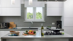 A modern kitchen with a large island, a built-in stove, and a window providing natural light. - Deep Blue in Labin With 3 Bedrooms and 2 Bathrooms (Labin)