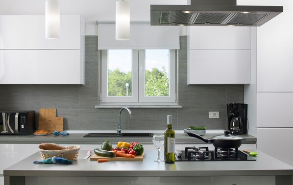 Uma cozinha moderna com uma ilha grande, fogão embutido e uma janela que traz luz natural.