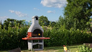 An outdoor grill with a chimney, surrounded by greenery and a clear sky. - Deep Blue in Labin With 3 Bedrooms and 2 Bathrooms (Labin)