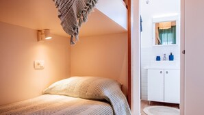 A bedroom with a bed, a bedside lamp, a window with curtains, and a bathroom with a sink and mirror. - Duzac in Kraj With 2 Bedrooms and 2 Bathrooms (Pasman)