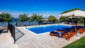 A swimming pool with lounge chairs and umbrellas, surrounded by a fence and trees. - Duzac in Kraj With 2 Bedrooms and 2 Bathrooms (Pasman)