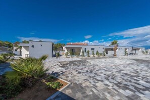 A modern residential area with white buildings, a paved courtyard, and small plants. - M3 in Vir With 2 Bedrooms and 2 Bathrooms (Vir)