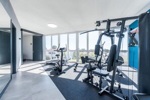 Ett modernt gym med träningsutrustning, stora fönster och utsikt över staden.
