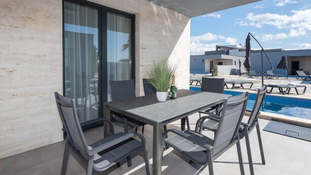 An outdoor patio with a table and chairs, a pool, and a view of the surrounding buildings. - M3 in Vir With 2 Bedrooms and 2 Bathrooms (Vir)