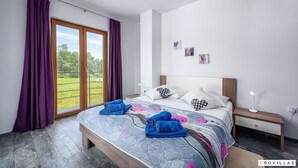 A bedroom with a bed, purple curtains, a view of greenery, and a wooden headboard. - Frankovici in Pazin With 3 Bedrooms and 2 Bathrooms (Pazin)