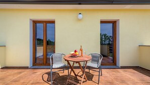 A balcony with a table, two chairs, a bottle, and a bowl of fruit. - Frankovici in Pazin With 3 Bedrooms and 2 Bathrooms (Pazin)